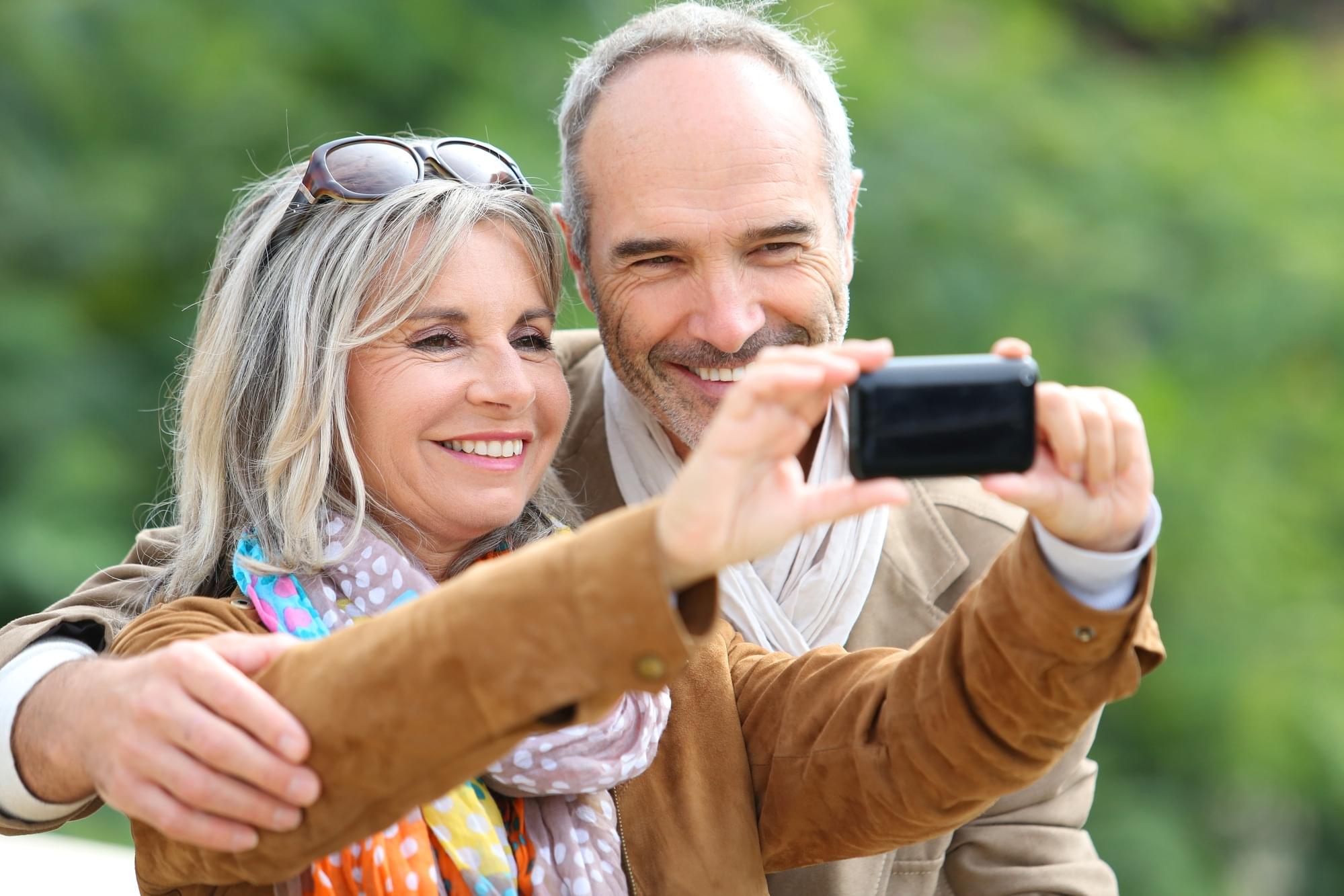 Cheerful senior couple taking picture with smartphone Cheerful senior couple taking picture with smartphone